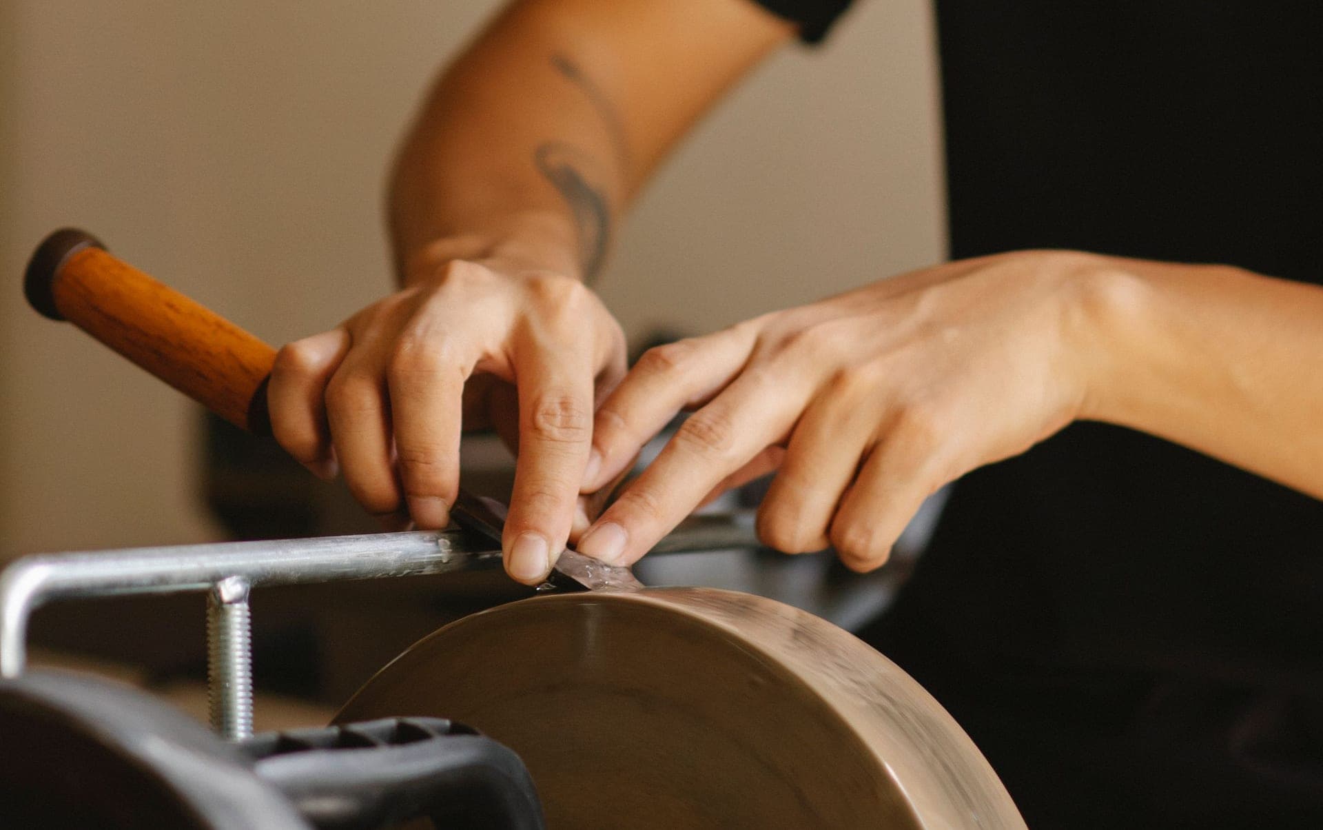 A craftsman grinding a chisel edge on a stone in a workshop