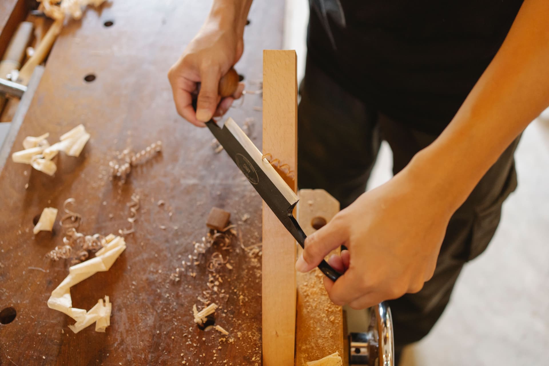 A woodworker cutting a joint by hand at a workbench